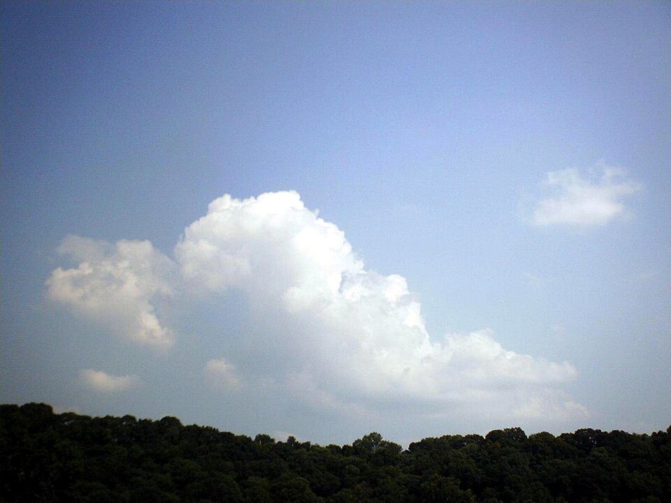 A white fair-weather cumulus cloud in a blue sky.
